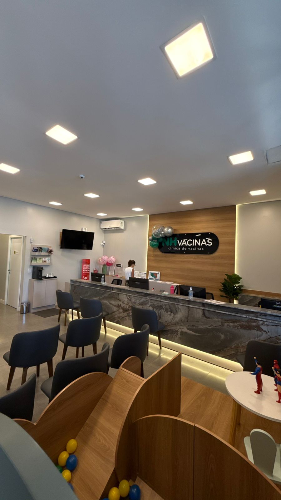 Recepção ampla da NH Vacinas com balcão de mármore escuro e logo na parede