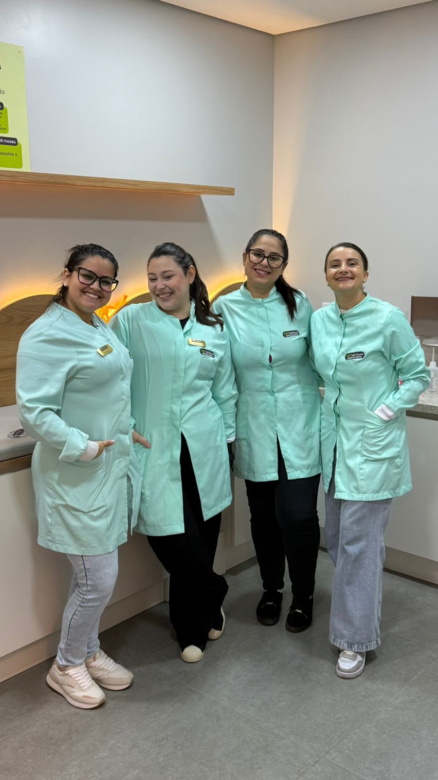Equipe de enfermeiras da NH Vacinas com uniformes mint sorrindo juntas