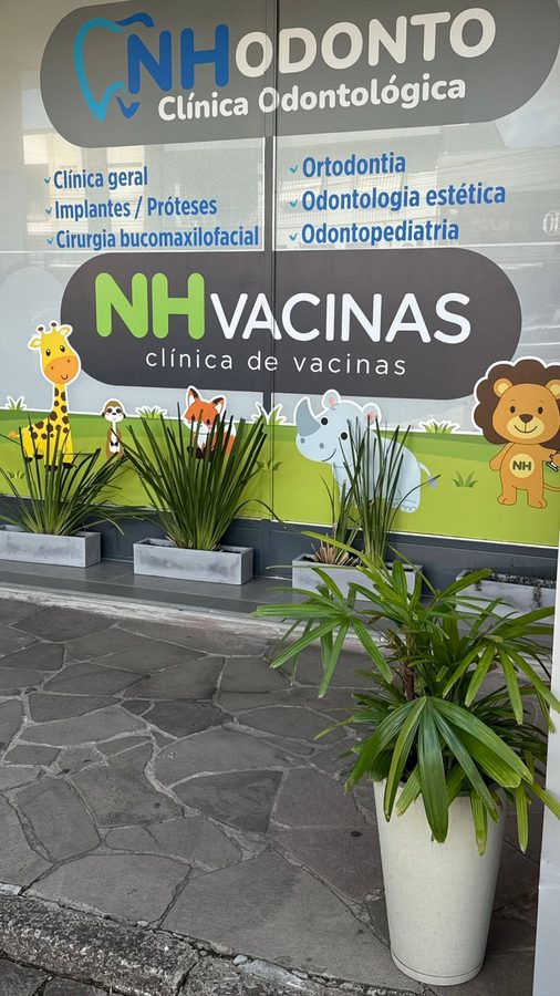 Fachada da NH Vacinas com decoração de animais e letreiro verde iluminado