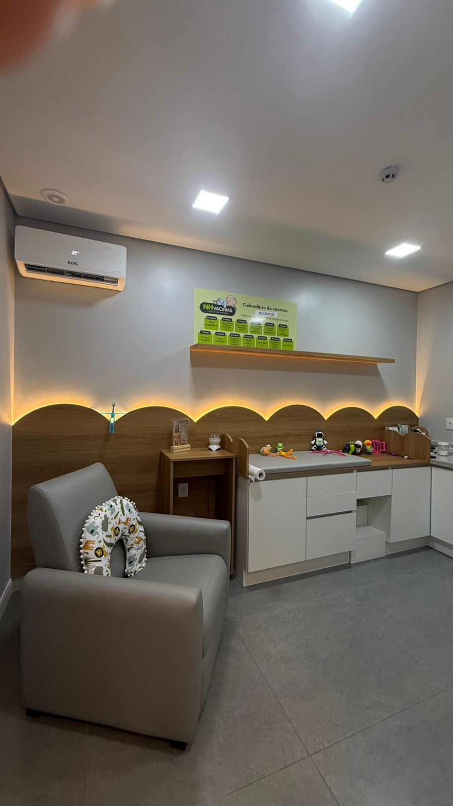 Sala de vacinação infantil com poltrona acolhedora, brinquedos e calendário na parede