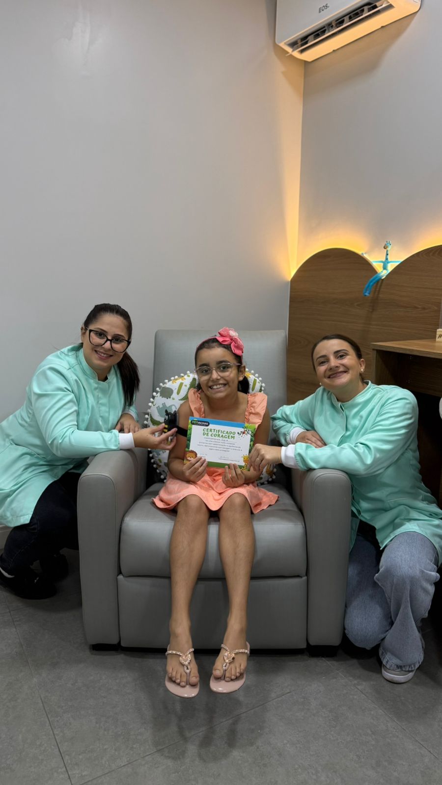 Duas enfermeiras da NH Vacinas com paciente criança segurando certificado de vacinação